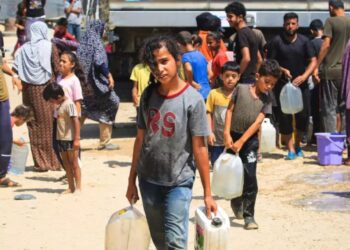 Palestinian children carrying water containers in a Gaza refugee camp under the summer sun, highlighting the region's clean water crisis.