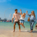 A smiling family enjoys a summer vacation in Dubai with iconic skyscrapers and sunny weather in the background.